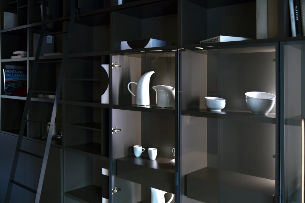 Stylish display of white ceramic tableware on dark shelving in contemporary setting.