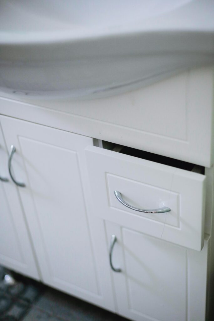 Close-up of a sleek white bathroom cabinet with drawer and sink in modern design.