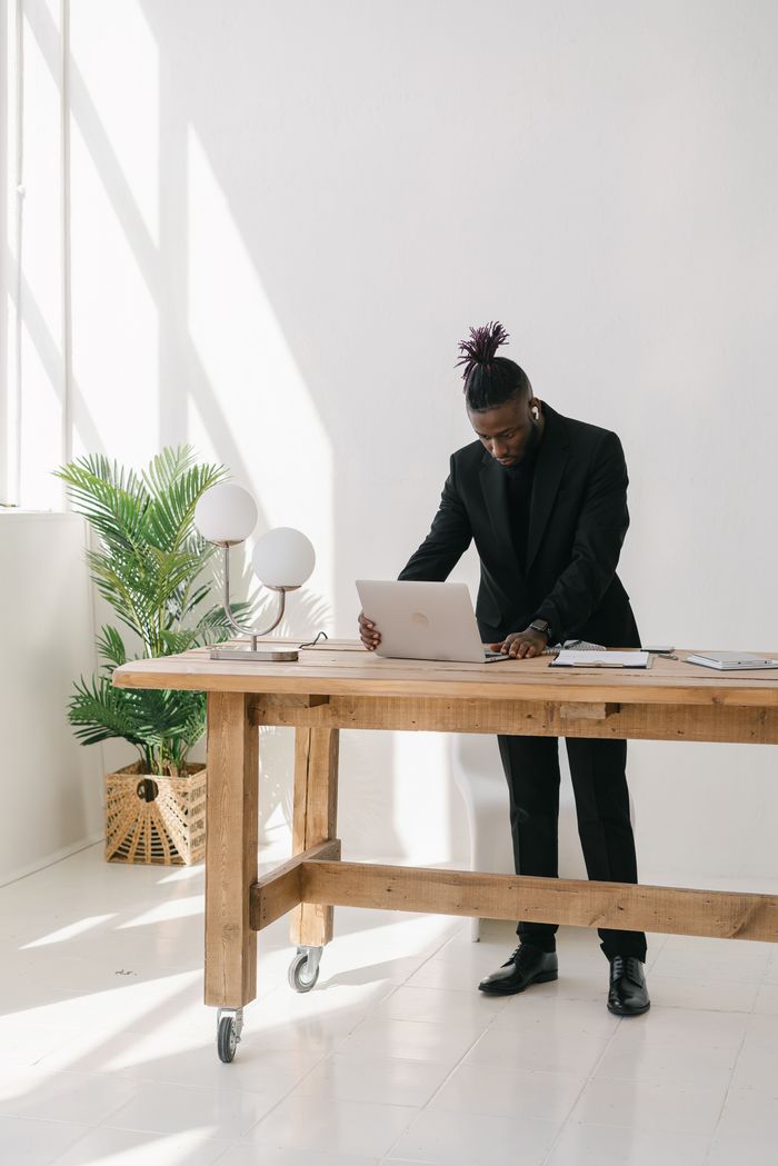 Focused businessman in a suit working on a laptop in a bright, minimalist office space.